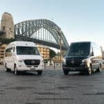 White and black 20 seat Mercedes Sprinter party limos parked in front of the Sydney Harbour Bridge at Circular Quay