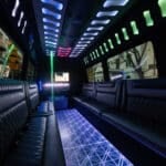 Interior of a 20 seater party limo in Sydney with an illuminated dance pole, champagne flutes on the ice bar and quilted leather lounge seating