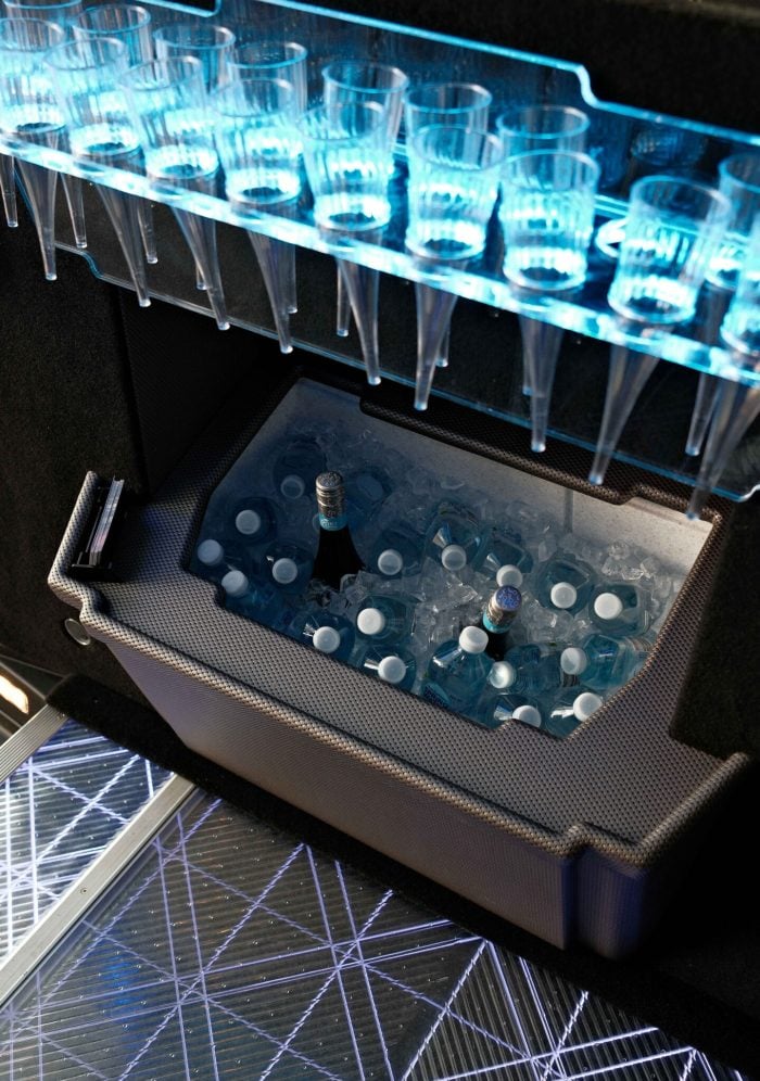 Built-in ice bar inside a black 20 seat party limo in Sydney, stocked with chilled drinks on ice and a rack of champagne flutes above the LED floor