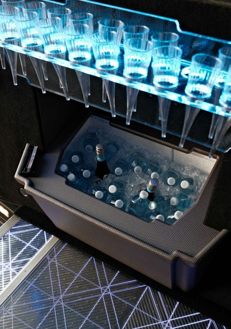 Built-in ice bar inside a black 20 seat party limo in Sydney, stocked with chilled drinks on ice and a rack of champagne flutes above the LED floor