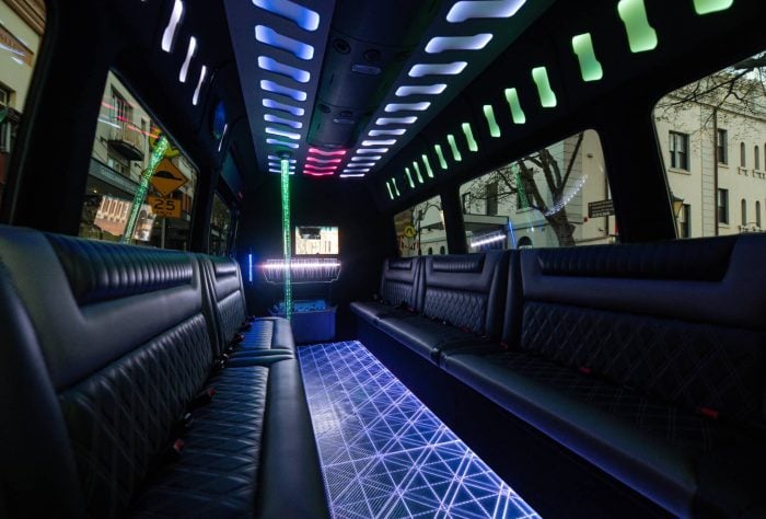 Interior of a 20 seater party limo in Sydney with an illuminated dance pole, champagne flutes on the ice bar and quilted leather lounge seating