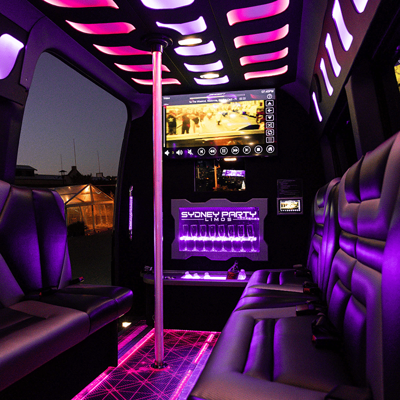 the inside of a party bus with bright lights and music video playing on screen parked up while on a trip in the Sutherland Shire